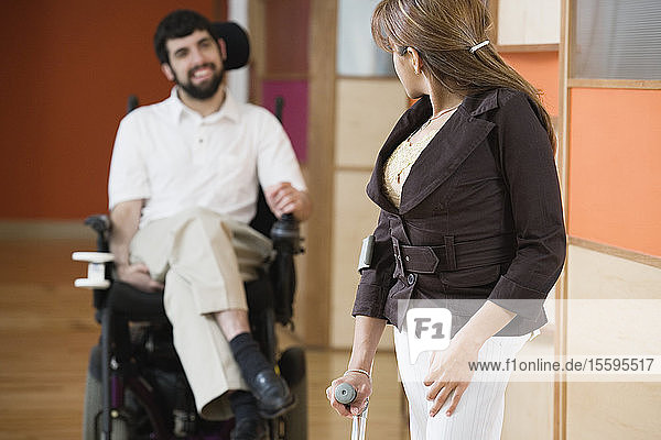 Young woman standing with a man with Cerebral Palsy smiling in the background