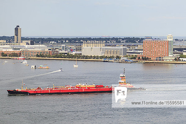 Tugboat moving tanker through Boston Harbor Logan Airport and East Boston Boston Massachusetts USA