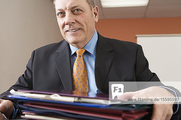 View of a businessman sitting with files in an office.