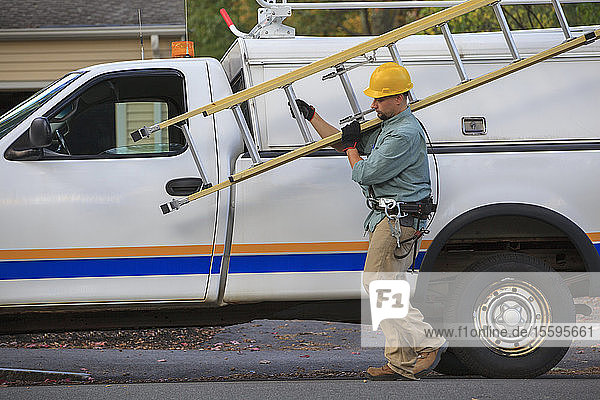 Ein Elektriker nimmt eine Leiter vom Lkw auf der Baustelle