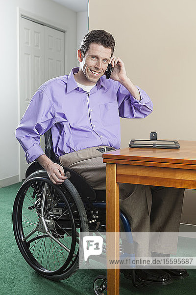 Mann im Rollstuhl mit Rückenmarksverletzung benutzt sein Mobiltelefon