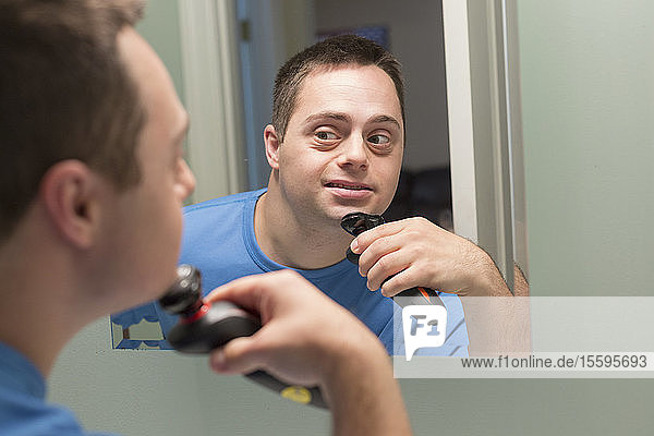Mann mit Down-Syndrom rasiert sich im Badezimmer