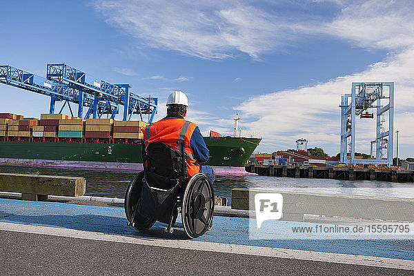 Transportingenieur im Rollstuhl bei der Inspektion eines Containerschiffs im Seehafen