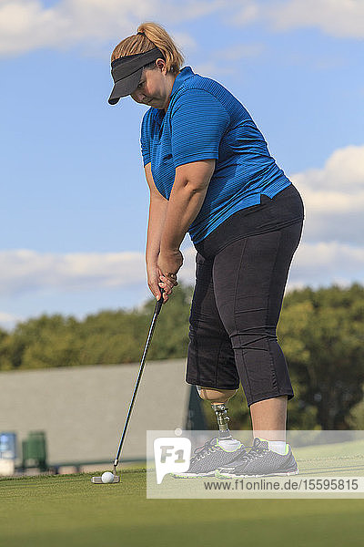 Frau mit Beinprothese beim Golf-Putting-Green