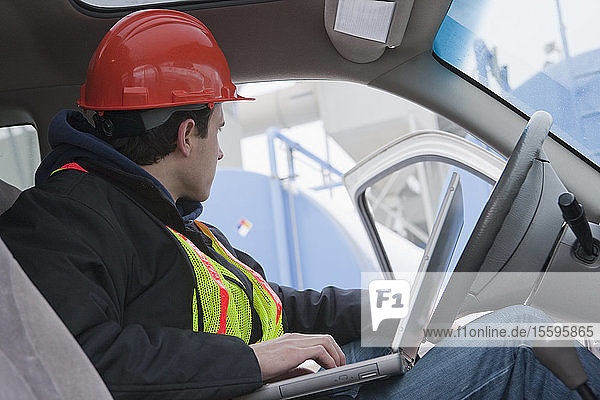 Engineer using a laptop in truck at fueling site