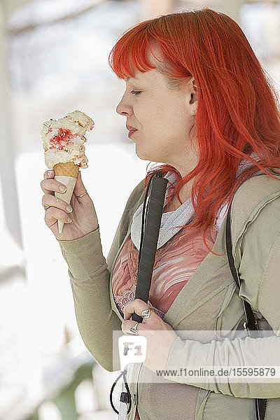 Junge blinde Frau mit Blindenstock genießt Eiscreme