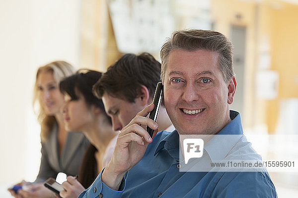 Man talking on a mobile phone and smiling with another passengers on an airport