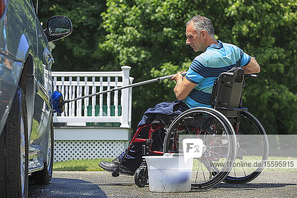 Man with a Spinal Cord Injury in wheelchair washing his accessible car