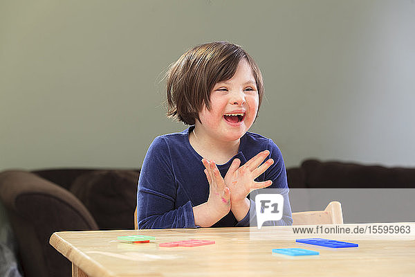 Kleines Mädchen mit Down-Syndrom spielt ein Lernspiel und lächelt