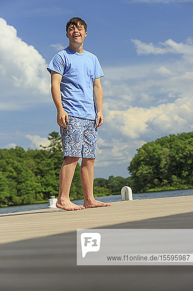 Happy young man with Down Syndrome standing on a dock
