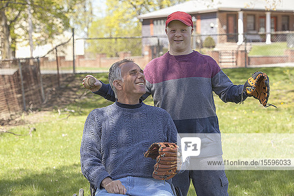Vater mit Rückenmarksverletzung und sein Sohn mit Down-Syndrom beim Baseballspielen im Park