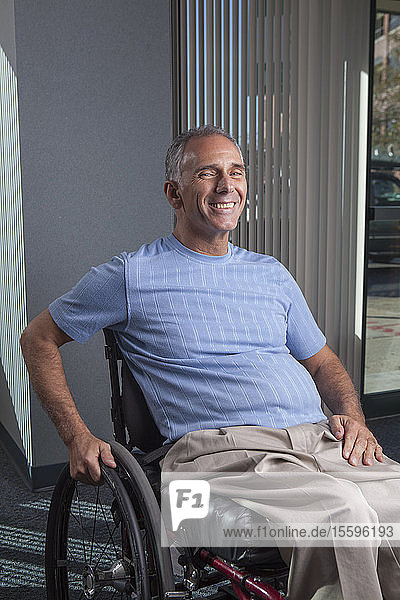Mann mit Querschnittslähmung im Rollstuhl in einem Büro