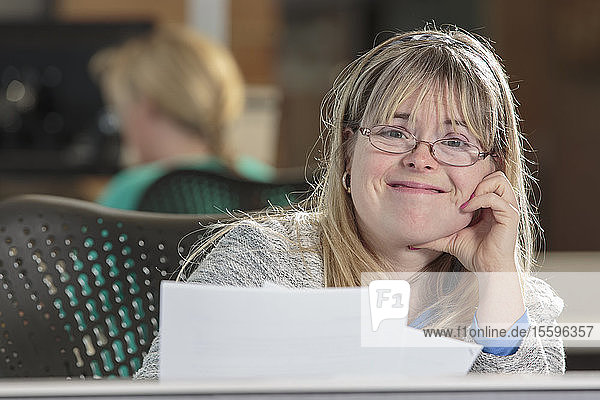 Junge Frau mit Down-Syndrom erledigt Papierkram in einem Büro
