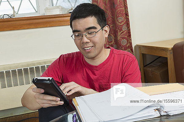 Glücklicher asiatischer Mann mit Autismus  der ein Telefon benutzt