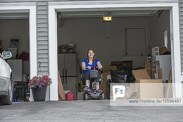 Junge Frau mit Cerebralparese steigt in der Garage auf ihren Motorroller