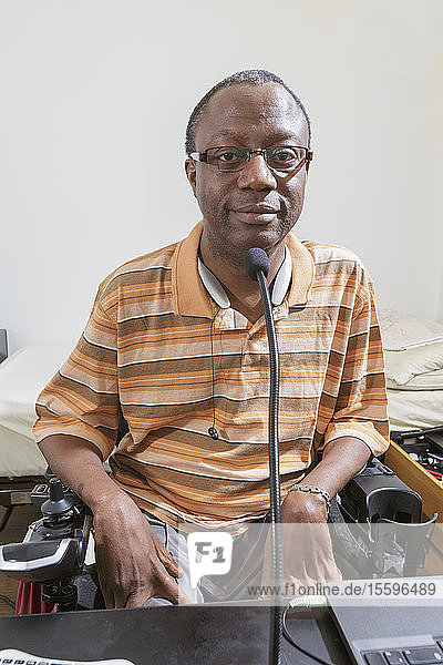 Mann mit Guillain-Barre-Syndrom bei der Nutzung seiner technischen Geräte im Heimbüro