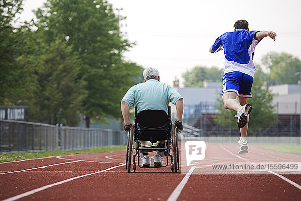 Rear view of a young man racing with a man in a wheelchair with Muscular Dystrophy
