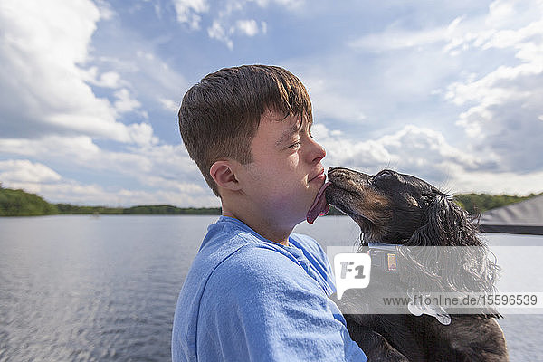 Young man with Down Syndrome playing with a dog on a dock