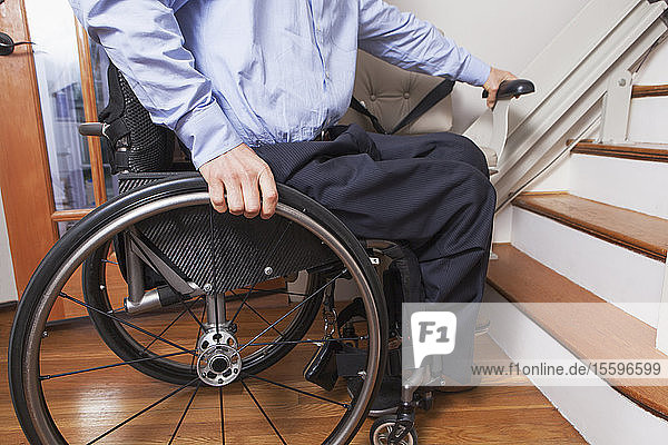 Mann mit Querschnittslähmung steigt in seinen motorisierten Treppenlift ein