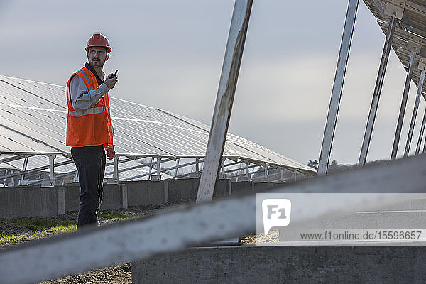 Power engineer at solar photovoltaic array and on radio