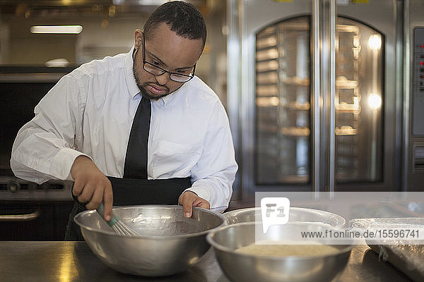 Afroamerikanischer Mann mit Down-Syndrom kocht als Koch in einer Großküche