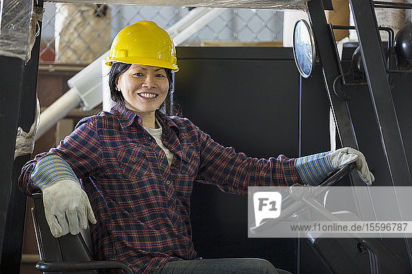 Weiblicher Energietechniker fährt einen Gabelstapler in einer Service-Werkstatt