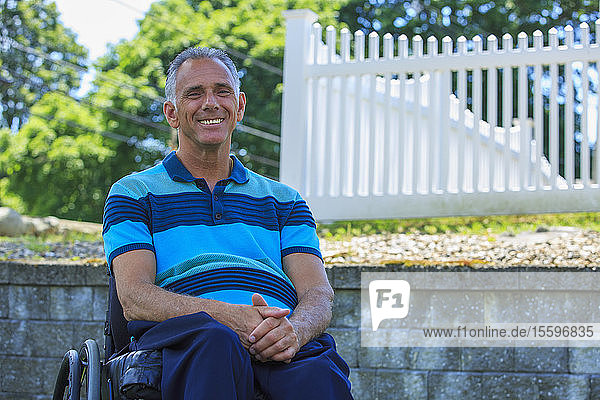 Lächelndes Porträt eines Mannes mit einer Querschnittslähmung im Rollstuhl