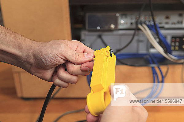 Kabelinstallateur beim Entfernen der äußeren Isolierung eines Kabels mit einem Werkzeug