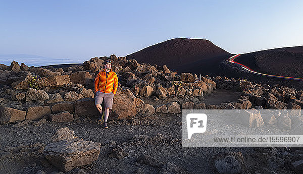 Mann  der auf schroffen Felsen über den Wolken auf dem Haleakala steht; Maui  Hawaii  Vereinigte Staaten von Amerika