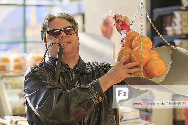 Man with congenital blindness weighing fruit at the grocery store