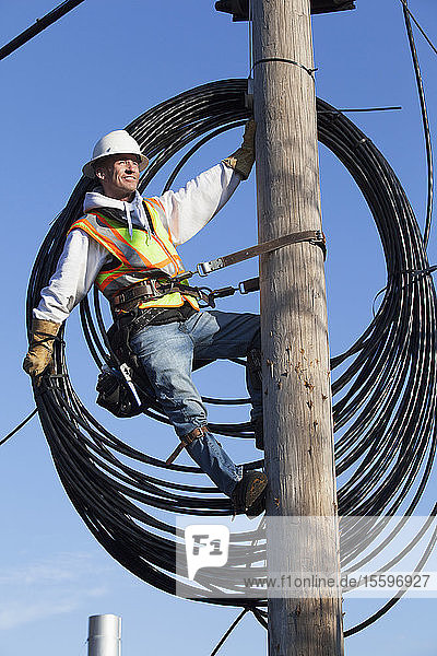 Kabelmonteur bei der Vorbereitung der Verlegung eines neuen Kabels vom Strommast