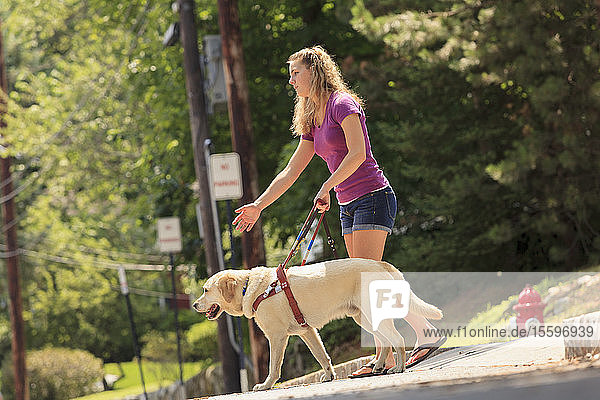 Studentin mit Sehbehinderung weist ihren Diensthund an  sich umzudrehen