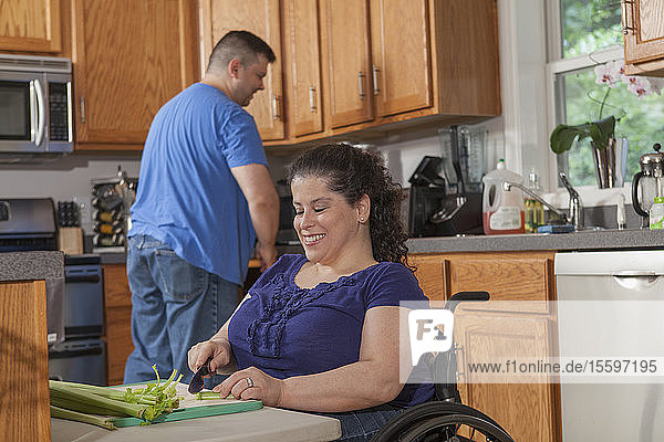 Frau mit Spina Bifida und ihr Mann bereiten das Abendessen in ihrer Küche vor