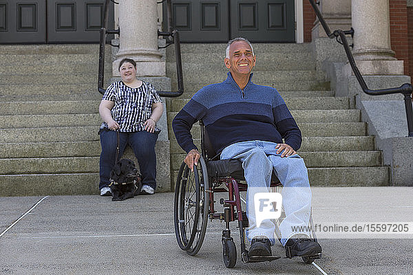 Man with Spinal Cord Injury sitting in wheelchair with his daughter in background who is Blind