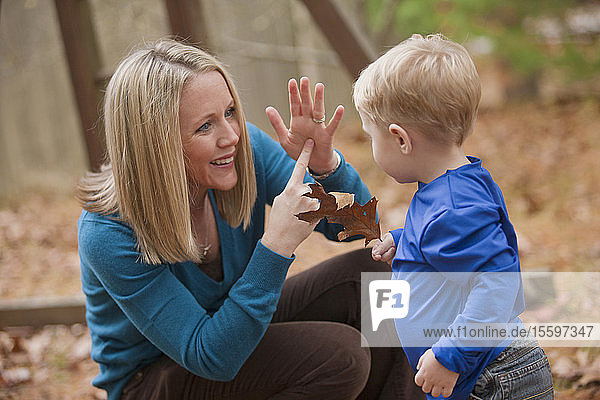 Frau gebärdet das Wort Leaf in amerikanischer Zeichensprache  während sie mit ihrem Sohn kommuniziert