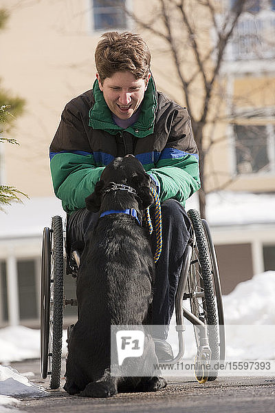 Frau mit Multipler Sklerose spielt im Winter mit einem Diensthund