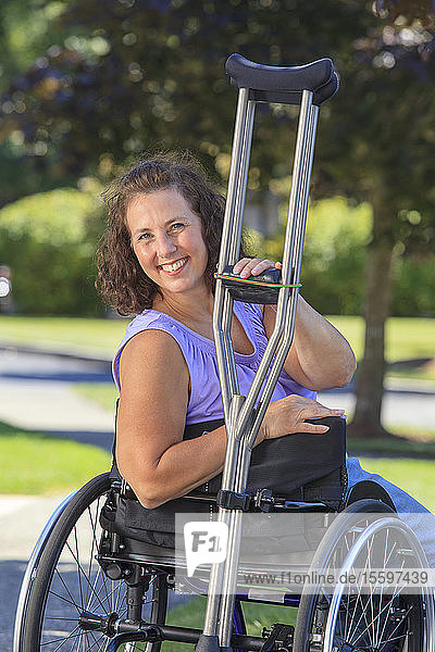 Frau mit Spina bifida und Rollstuhl mit Krücken