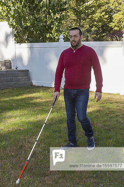 Mann mit Sehbehinderung benutzt seinen Stock im Freien