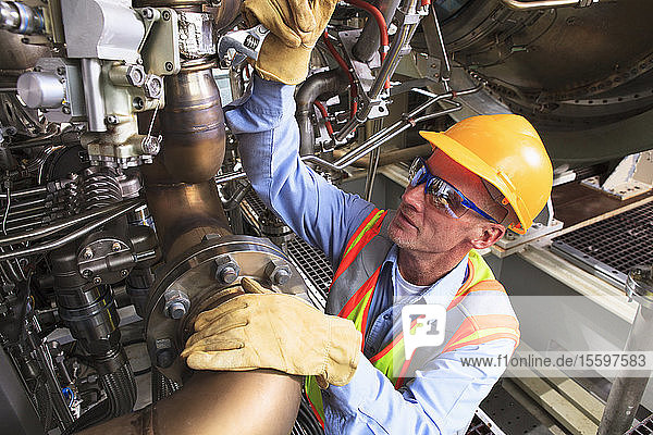 Engineer at turbine stage of gas turbine which drives generators in power plant while turbine is powered down