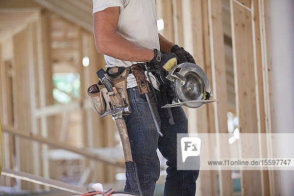 Spanischer Zimmermann bei der Arbeit mit einer Kreissäge in einem im Bau befindlichen Haus