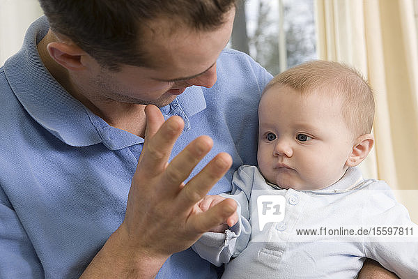 Mann gebärdet das Wort Mommy in amerikanischer Zeichensprache  während er mit seinem Sohn kommuniziert