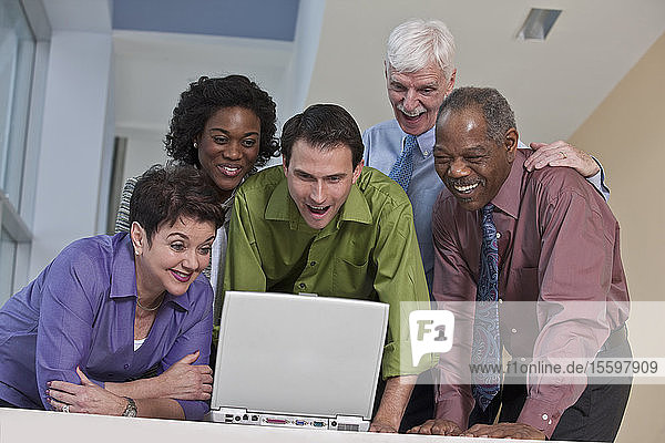 Business executives using a laptop and smiling