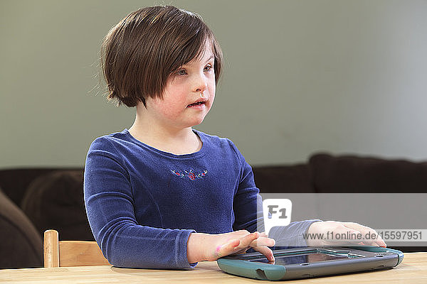 Kleines Mädchen mit Down-Syndrom spielt ein elektronisches Lernspiel
