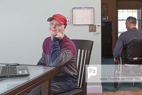 Happy young man with Down Syndrome and his father in wheelchair with Spinal Cord Injury at home