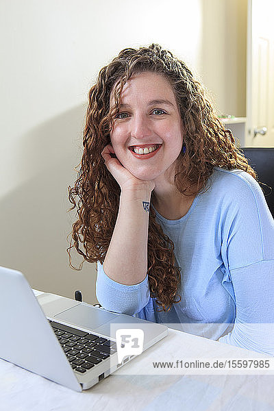 Frau mit Muskeldystrophie arbeitet an ihrem Laptop in ihrem Büro