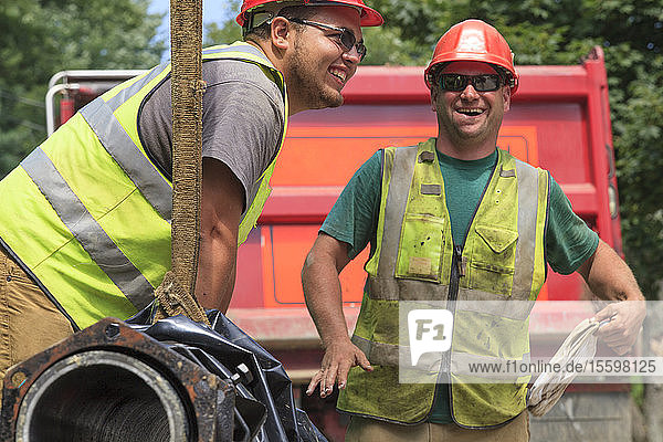 Construction workers guiding water main into place