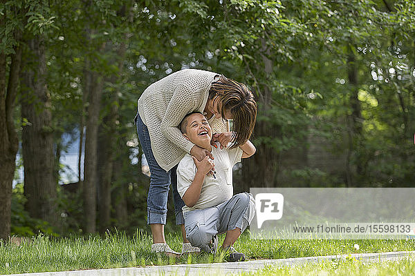 Hispanischer Junge mit Autismus spielt draußen mit seiner Mutter