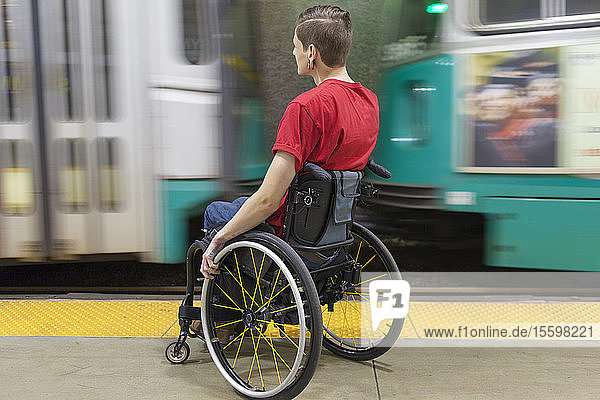 Trendy man with a spinal cord injury in wheelchair waiting for a subway train