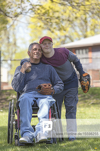 Vater mit Rückenmarksverletzung und sein Sohn mit Down-Syndrom beim Baseballspielen im Park
