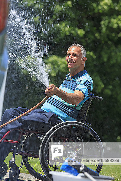 Man with a Spinal Cord Injury in wheelchair washing his accessible car